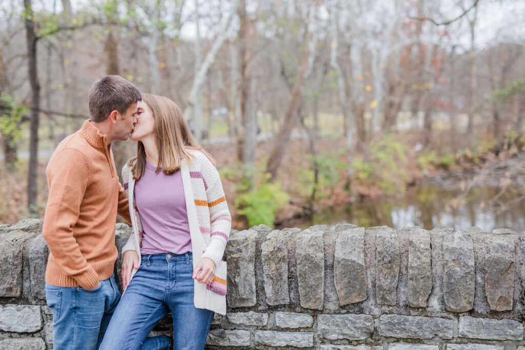 engaged couple kisses on the bridge at sharon woods