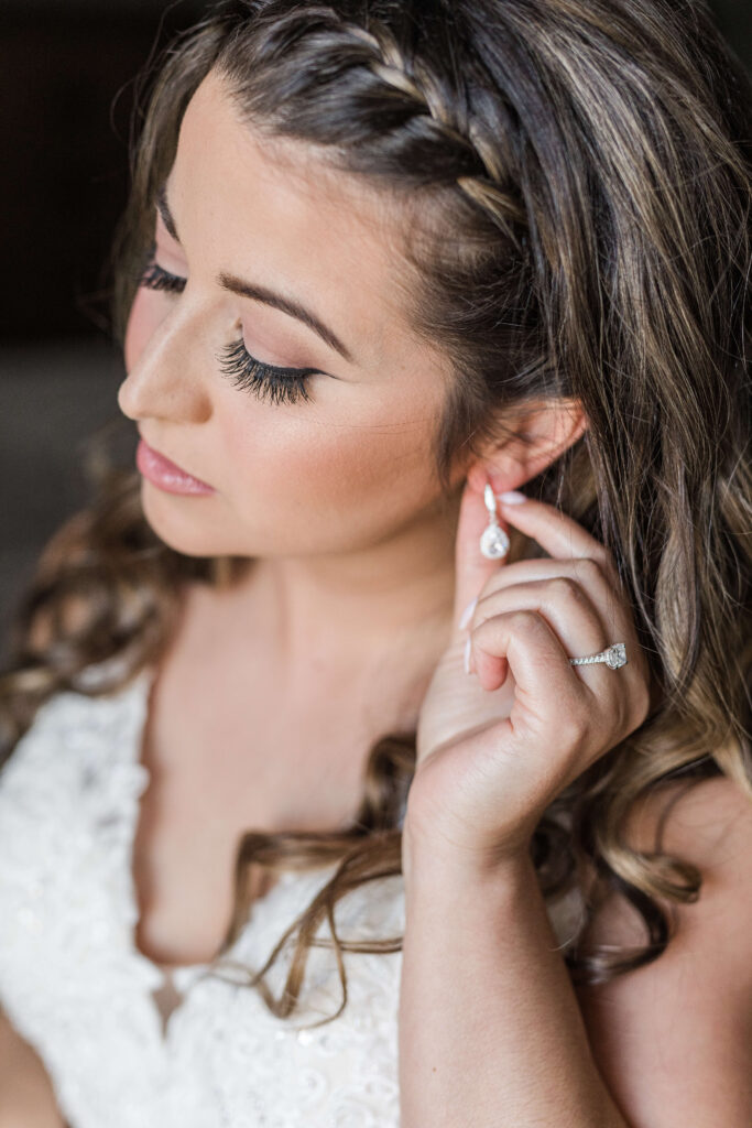 bride putting on earrings on her wedding day