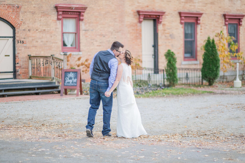 bride and groom kiss in front of the building at shuey mill