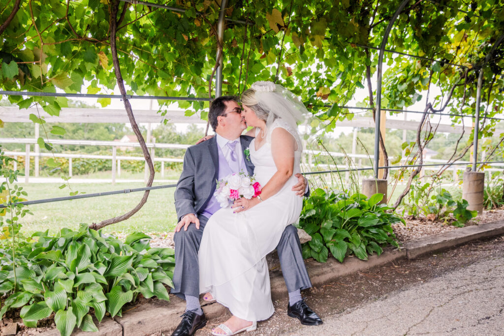 bride and groom kiss while sitting down at vinoklet winery