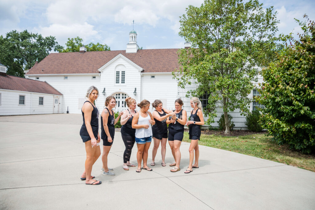 bride and bridesmaids attempt to pop a champagne bottle at the barn in mariemont