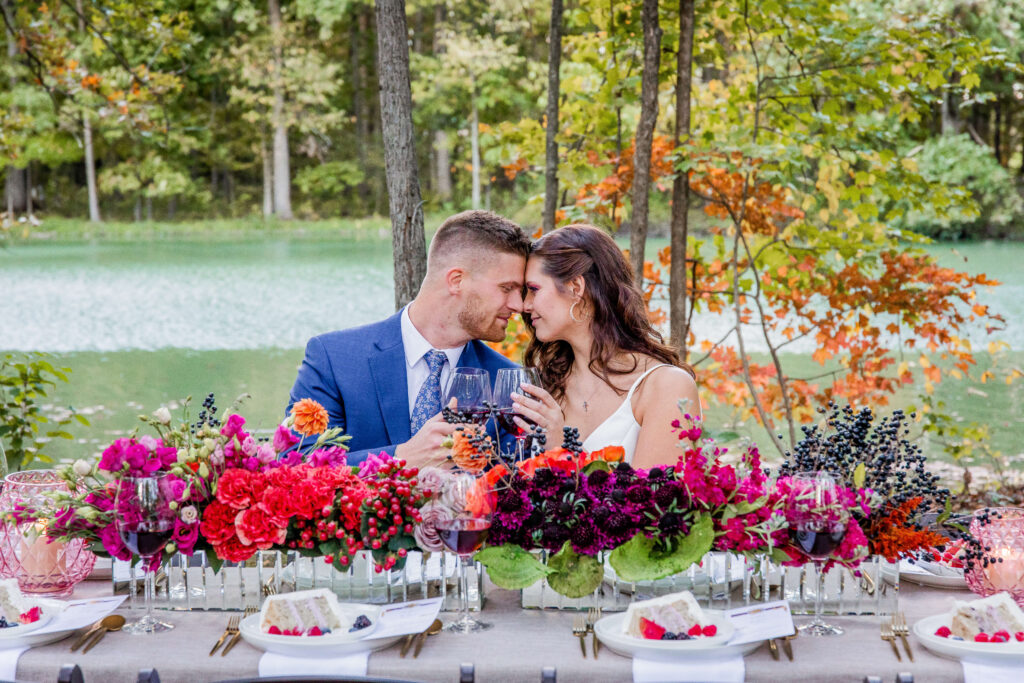 wedding photographer captures couple sitting at their table with lots of foliage and flowers in the background