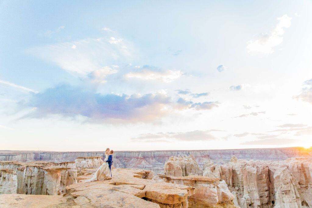 bride and groom stand at the edge of the grand canyon while the sun sets. taken by cincinnati wedding photographer.