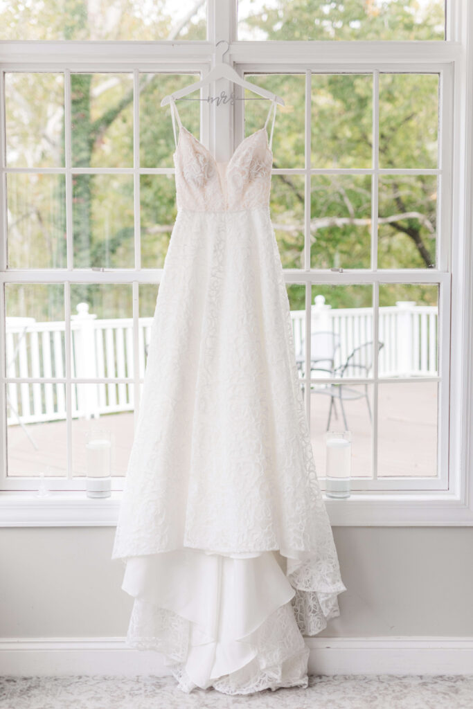 brides dress hanging in window at bel-wood country club