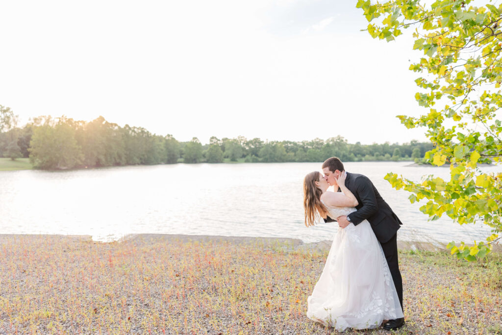 A bride and groom kiss as the sun is setting on a lake at Lake Lyndsay
